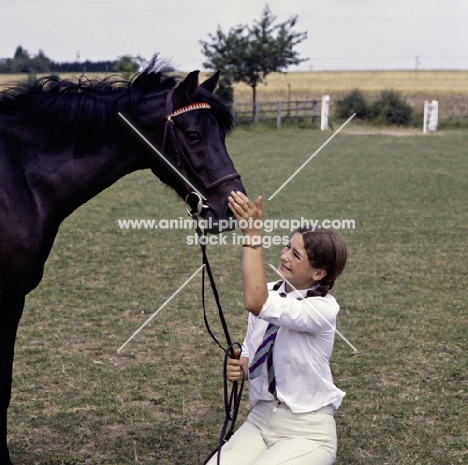 child patting her pony on the nose