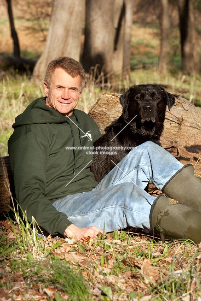 man sitting with black labrador