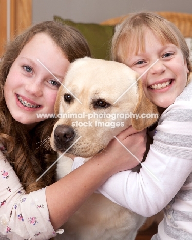 girls hugging a Labrador