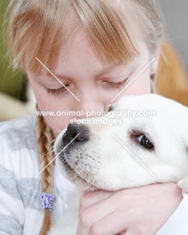 girl kissing her Labrador puppy